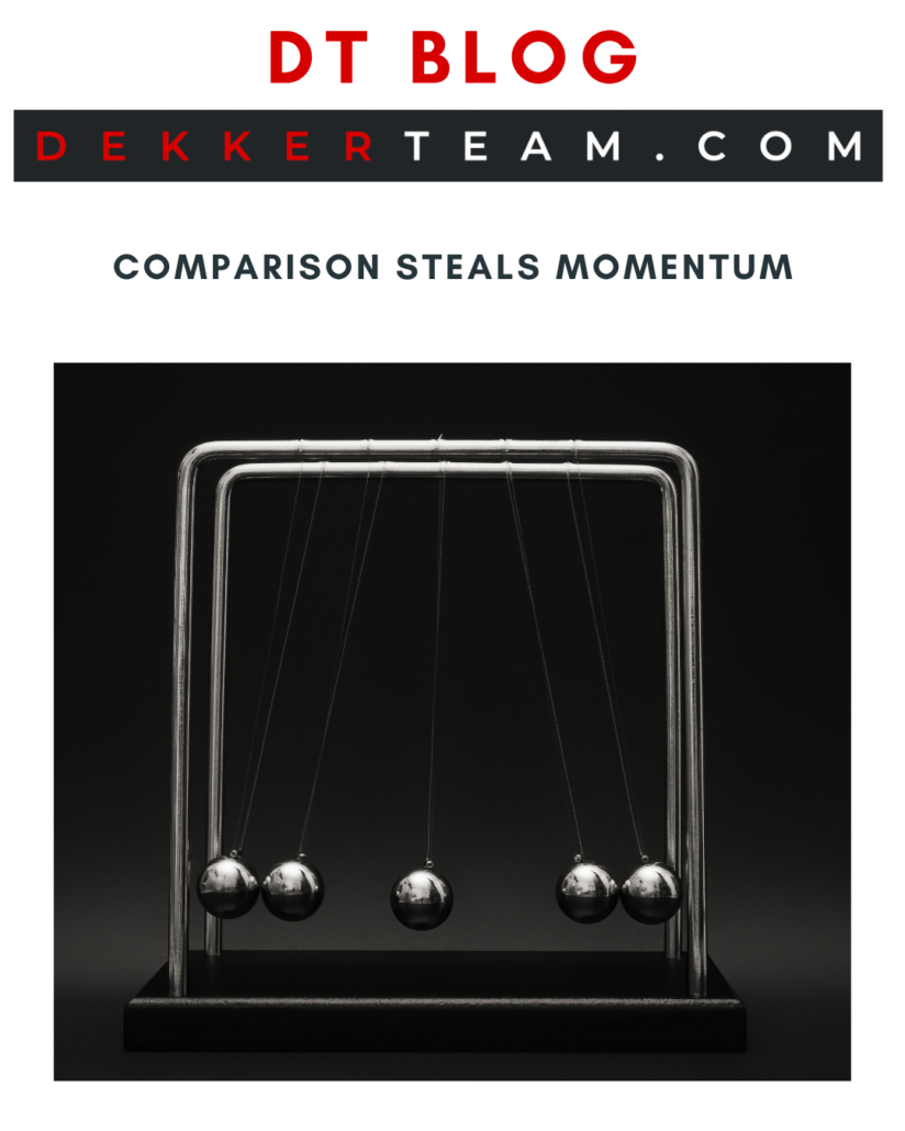DT blog
COMPARISON STEALS MOMENTUM
DekkerTeam.com

A Newton's cradle with several metal spheres hanging from a frame.
