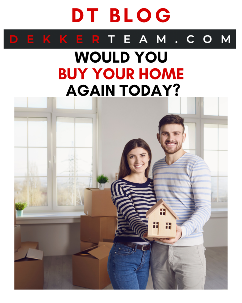 Two people standing indoors near a window, one holding a house - both smiling at the camera. DT blog Would You Buy Your Home Again Today? 
